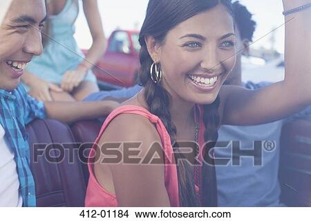 Picture - Smiling friends riding in convertible. Fotosearch
