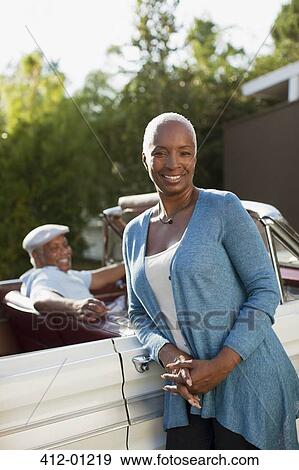 Smiling older woman leaning on convertible View Large Photo Image Stock Photo - Smiling older woman leaning on convertible. Fotosearch