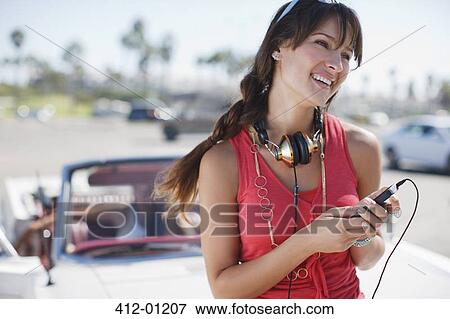 Stock Photo - Smiling woman holding mp3 player. Fotosearch