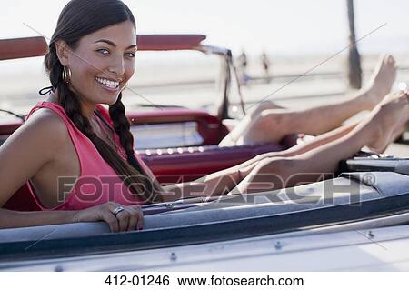 Smiling woman relaxing in convertible View Large Photo Image Stock Photograph - Smiling woman relaxing in convertible. Fotosearch