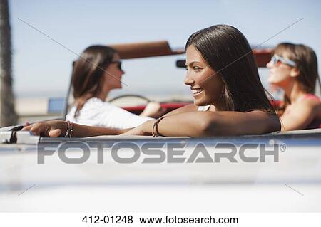 Smiling woman sitting in convertible View Large Photo Image Stock Photo - Smiling woman sitting in convertible. Fotosearch