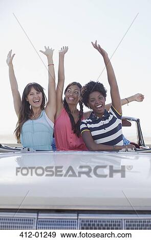 Smiling women cheering in convertible View Large Photo Image Stock Photo - Smiling women cheering in convertible. Fotosearch