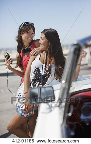 Smiling women leaning on convertible View Large Photo Image Stock Photograph - Smiling women leaning on convertible. Fotosearch
