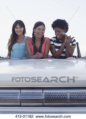 Smiling women sitting in convertible View Large Photo Image Stock Image - Smiling women sitting in convertible. Fotosearch