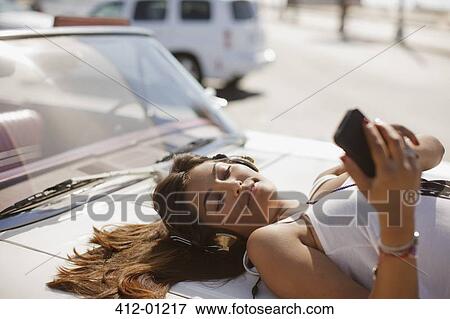 Woman listening to mp3 player on convertible View Large Photo Image Stock Photo - Woman listening to mp3 player on convertible. Fotosearch