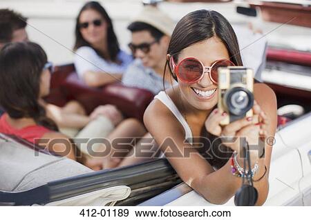 Woman taking picture from convertible View Large Photo Image Stock Photo - Woman taking picture from convertible. Fotosearch