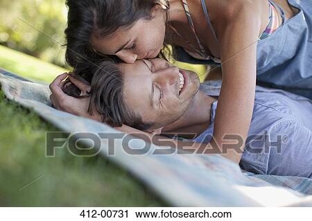 Affectionate couple laying on blanket in grass View Large Photo Image Stock Image - Affectionate couple laying on blanket in grass. Fotosearch