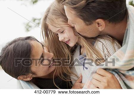 Stock Photo - Close up of happy family wrapped in blanket. Fotosearch