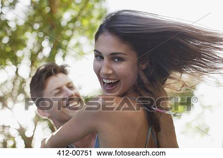 Stock Image - Close up of man spinning smiling girlfriend. Fotosearch