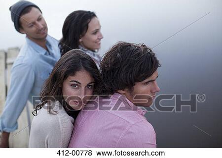 Stock Photo - Couples sitting on dock over lake. Fotosearch