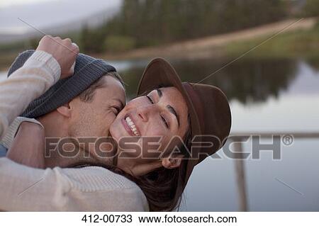 Stock Image - Enthusiastic couple hugging at lakeside. Fotosearch