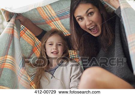 Stock Photo - Enthusiastic mother and daughter under blanket. Fotosearch