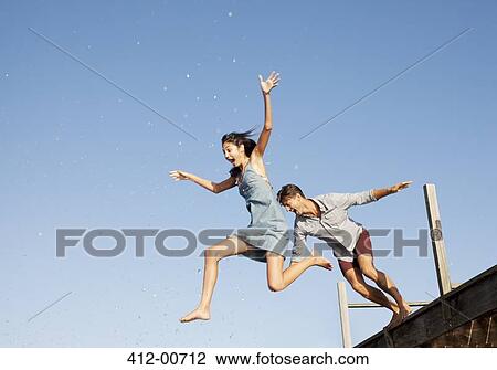 Exuberant couple jumping off dock View Large Photo Image Stock Image - Exuberant couple jumping off dock. Fotosearch
