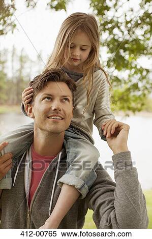 Stock Photography - Father carrying daughter on shoulders at lakeside. Fotosearch