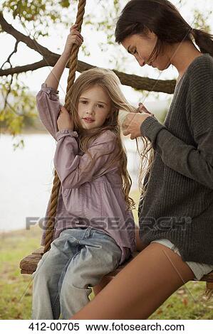Mother braiding daughter's hair on swing at lakesid View Large Photo Image Stock Photography - Mother braiding daughter's hair on swing at lakesid. Fotosearch