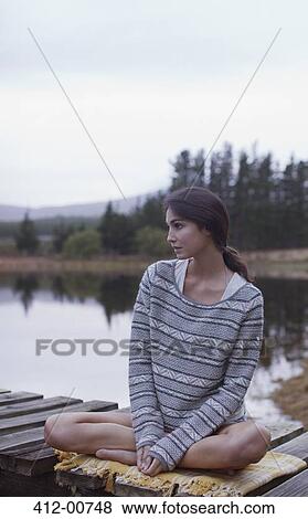 Pensive woman sitting on dock at lake View Large Photo Image Stock Photo - Pensive woman sitting on dock at lake. Fotosearch