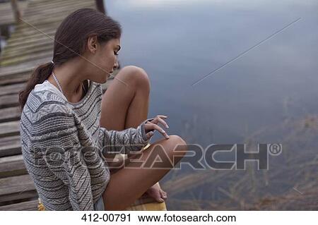 Pensive woman sitting on dock over lake View Large Photo Image Stock Image - Pensive woman sitting on dock over lake. Fotosearch
