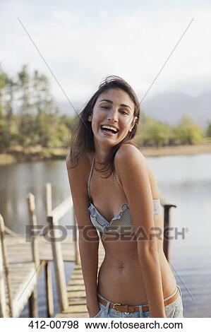 Stock Photo - Portrait of enthusiastic woman in bikini at lakeside. Fotosearch