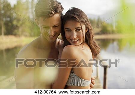 Portrait of smiling couple hugging at lakeside View Large Photo Image Picture - Portrait of smiling couple hugging at lakeside. Fotosearch