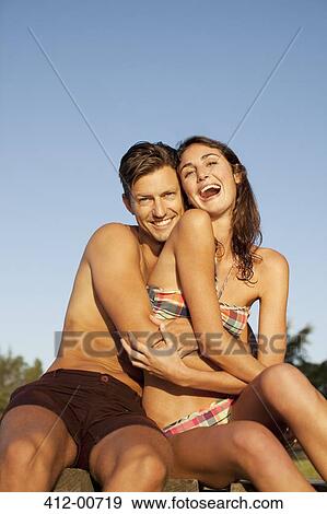 Portrait of smiling man hugging enthusiastic woman in bikini View Large Photo Image Stock Photo - Portrait of smiling man hugging enthusiastic woman in bikini. Fotosearch