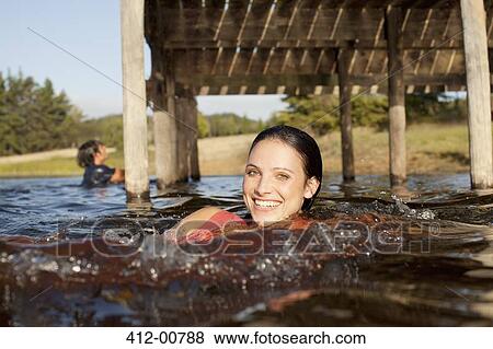 Portrait of smiling woman swimming in lake under dock View Large Photo Image Stock Photo - Portrait of smiling woman swimming in lake under dock. Fotosearch