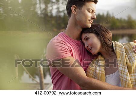 Stock Image - Serene couple hugging at lakeside. Fotosearch