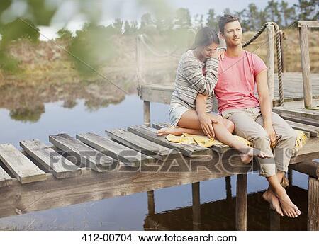 Serene couple siting on dock over lake View Large Photo Image Picture - Serene couple siting on dock over lake. Fotosearch