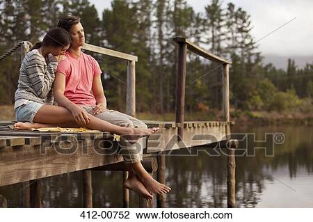 Serene couple sitting at edge of dock over lake View Large Photo Image Stock Image - Serene couple sitting at edge of dock over lake. Fotosearch