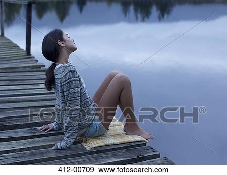 Serene woman sitting on dock over lake View Large Photo Image Stock Photo - Serene woman sitting on dock over lake. Fotosearch