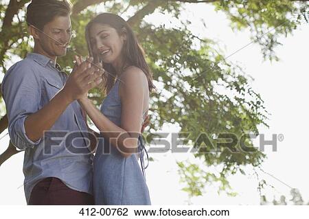 Smiling couple holding hands under tree View Large Photo Image Stock Image - Smiling couple holding hands under tree. Fotosearch