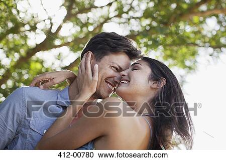 Smiling couple hugging under tree View Large Photo Image Stock Image - Smiling couple hugging under tree. Fotosearch