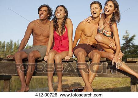 Smiling couples sitting at edge of dock View Large Photo Image Stock Photograph - Smiling couples sitting at edge of dock. Fotosearch