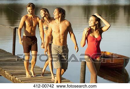 Smiling couples walking on dock over lake View Large Photo Image Stock Image - Smiling couples walking on dock over lake. Fotosearch