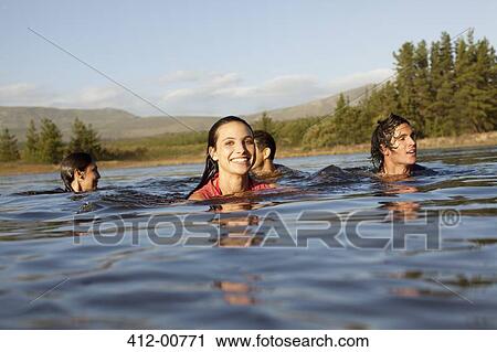 Stock Image - Smiling friends swimming in lake. Fotosearch