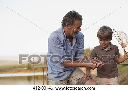 Smiling grandfather and grandson fishing at lakeside View Large Photo Image Stock Photography - Smiling grandfather and grandson fishing at lakeside. Fotosearch