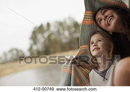 Smiling mother and daughter under blanket at lakeside View Large Photo Image Stock Photo - Smiling mother and daughter under blanket at lakeside. Fotosearch