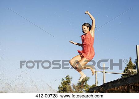 Smiling woman jumping off dock View Large Photo Image Stock Photo - Smiling woman jumping off dock. Fotosearch