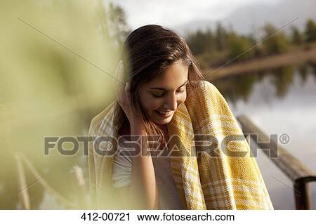 Smiling woman wrapped in blanket at lakeside View Large Photo Image Stock Image - Smiling woman wrapped in blanket at lakeside. Fotosearch
