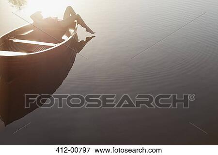 Woman laying in boat on sunny lake View Large Photo Image Stock Photo - Woman laying in boat on sunny lake. Fotosearch