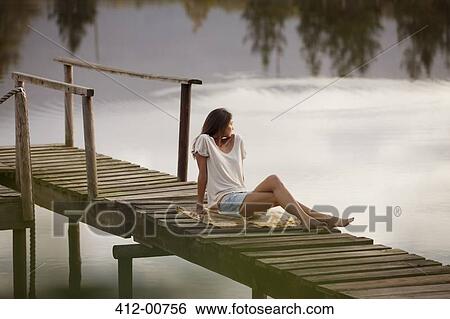 Woman sitting on dock over lake View Large Photo Image Stock Photograph - Woman sitting on dock over lake. Fotosearch