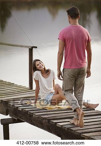 Woman smiling at approaching man on dock over lake View Large Photo Image Stock Photo - Woman smiling at approaching man on dock over lake. Fotosearch