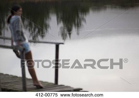 Woman standing on dock over lake View Large Photo Image Stock Photography - Woman standing on dock over lake. Fotosearch