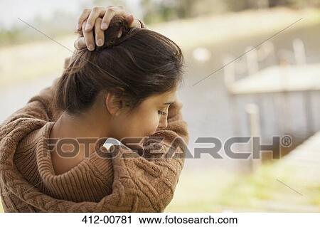 Stock Image - Woman with hands in hair at lakeside. Fotosearch