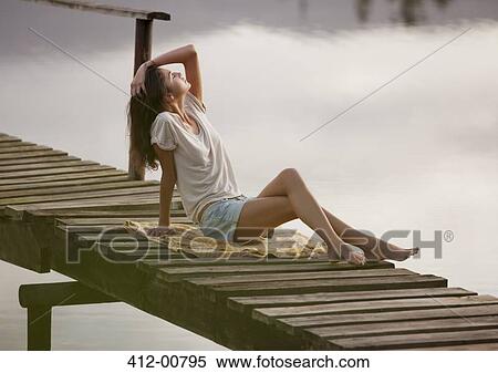 Woman with head back and hand in hair on dock over lake View Large Photo Image Stock Photography - Woman with head back and hand in hair on dock over lake. Fotosearch
