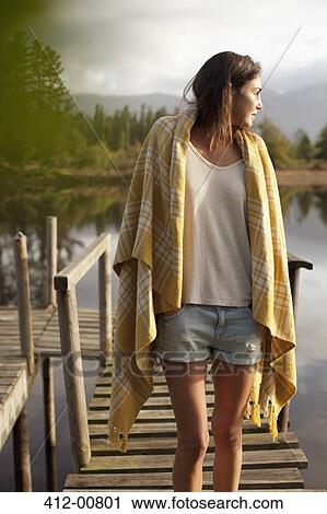 Woman wrapped in blanket standing on dock over lake View Large Photo Image Stock Image - Woman wrapped in blanket standing on dock over lake. Fotosearch