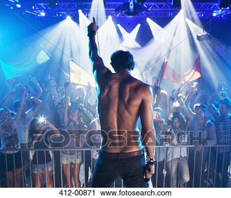 Bare chested musician standing with arm raised before crowd View Large Photo Image Stock Image - Bare chested musician standing with arm raised before crowd. Fotosearch
