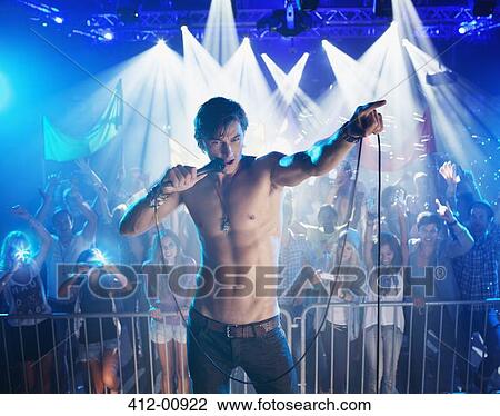 Bare chested singer performing with crowd in background View Large Photo Image Stock Image - Bare chested singer performing with crowd in background. Fotosearch