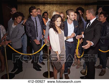 Bouncer granting couple access outside nightclub View Large Photo Image Stock Photo - Bouncer granting couple access outside nightclub. Fotosearch