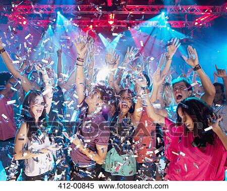 Stock Photography - Confetti falling over enthusiastic crowd on dance floor of nightclub. Fotosearch