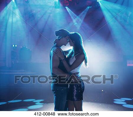 Stock Photo - Couple dancing and kissing under spotlights on empty dance floor of nightclub. Fotosearch